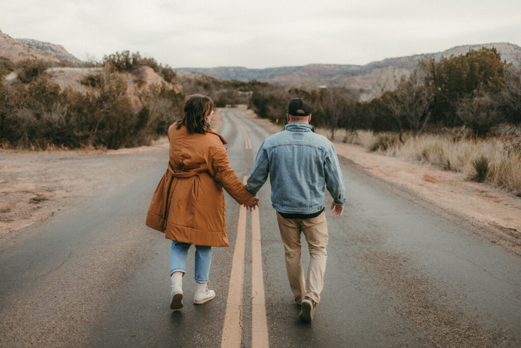Couple holding hands walking down road 